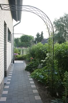 the walkway is lined with green plants and shrubs, along with a brick building in the background