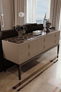 a living room area with a couch, sideboard and large window overlooking the city