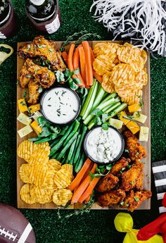 a football platter with chicken wings, carrots, celery and chips