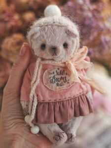 a small teddy bear wearing a pink dress