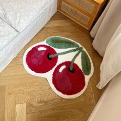 a rug with two cherries on it in the middle of a floor next to a bed