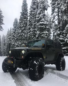 a jeep driving through the snow in front of some trees