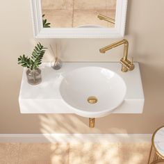 a white sink sitting under a mirror next to a table with a potted plant