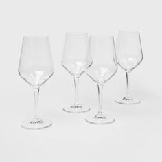 four wine glasses sitting next to each other on a white surface with one empty glass in the middle