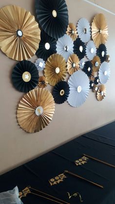 decorative paper fans hanging on the wall in a room with gold and black decorating