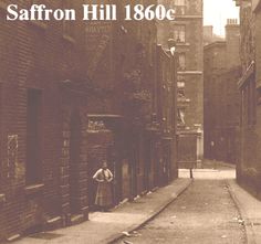 an old photo of a man standing in the middle of a narrow alleyway between two buildings