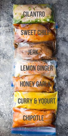 four sandwiches wrapped in plastic sitting on top of each other, labeled with different ingredients