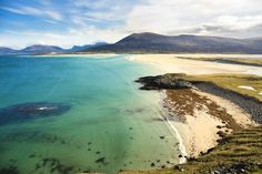 an aerial view of the beach and ocean with mountains in the backgrouund