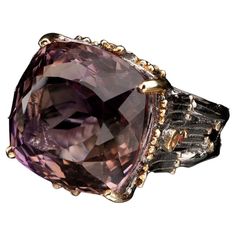 This large and flawless deep purple natural amethyst has been square-cut and placed in a uniquely and intricately hand-carved rhodium plated sterling silver prong setting and band both tastefully ornamented with luxe gold leaf. One round pink and one rare yellow sapphire accent the ring on each side. We resize within 10 business days for a $25 fee. If you select the resize option, please add a note with your order or email us with the size to which you would like your ring adjusted. Size: 7 Dimensions: 20mmW x 30mmD x 18mmH Weight: 12.83 g Square Cut, Yellow Sapphire, Amethyst Ring, Ring Ring, Deep Purple, Gold Leaf, Rhodium Plated, Prong Setting, Sapphire Ring