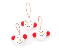 three red and white ornaments hanging from strings on a white surface, one with a snowman's head