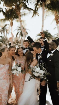 a group of people standing next to each other in front of palm trees and flowers