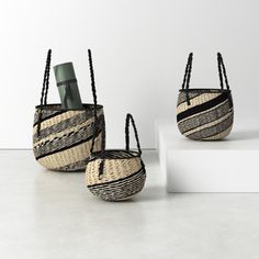 three woven baskets sitting on top of a white shelf next to each other and one has a bottle in it