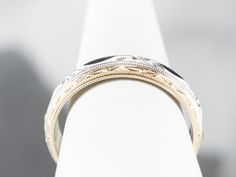 This vintage band is crafted entirely of 14k gold, with yellow gold framing the edge of the ring, and white gold creating a floral accented center. The center of this ring is slightly domed, giving it the ability to catch the light and accented by the waving, faceted edge. Metal: 14K Yellow and White Gold Width of Band: 6.5 mm Height off Finger: 2.1 mm Ring Size: 12.25 Marks: "14KT" Stamped on the inside band Timeless White Gold Bands With Decorative Detail, Classic Round Diamond Ring With Decorative Band, Classic Diamond Ring With Decorative Band, Classic Diamond Ring With Decorative Band For Formal Events, Timeless Formal Rings With Decorative Band, Classic Formal Diamond Ring With Decorative Band, Heirloom Diamond Ring With Decorative Band For Formal Occasions, Luxury White Gold Engraved Ring With Decorative Band, Luxury White Gold Ring With Decorative Band