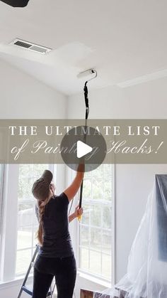 a woman is painting the ceiling in her living room with white paint and black rollers