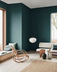 a living room with teal walls and white furniture in the corner, including a rocking chair