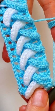 someone is crocheting the end of a piece of blue and white yarn with scissors