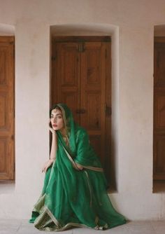 a woman in a green sari sitting on the floor