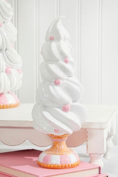 there is a white frosted cupcake on top of a pink cake stand next to a book