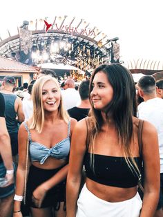 two beautiful women standing next to each other in front of a crowd at a music festival