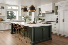 a kitchen with white cabinets, green island and gold pendant lights hanging from the ceiling