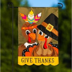 a thanksgiving flag with two turkeys wearing pilgrim hats and the words give thanks on it