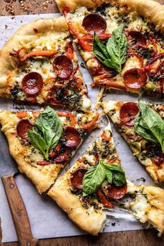 a pizza cut into eight slices on top of a cutting board with basil and pepperoni