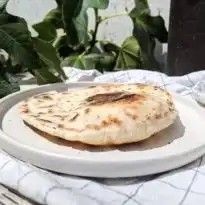 a white plate topped with an uncooked flat bread on top of a table