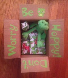 a green stuffed animal in a cardboard box with the words be happy today written on it