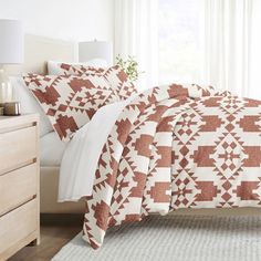 a bed in a bedroom with white and brown sheets, pillows and blankets on top of it