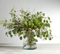 a vase filled with lots of green plants