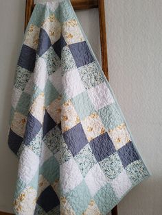 a blue and white checkered quilt hanging from a wooden ladder next to a wall