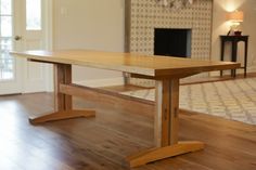 a wooden table sitting on top of a hard wood floor next to a fire place