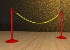 two red poles with yellow rope on them in front of a black wall and wooden floor