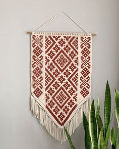 a red and white wall hanging next to a potted plant