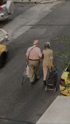 an older couple walking down the street with their baby carriage and stroller in tow