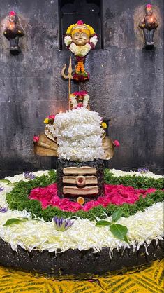 an elaborately decorated cake on display in front of a wall with candles and flowers