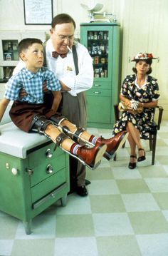 an old man is sitting on top of a stove while two women look at him