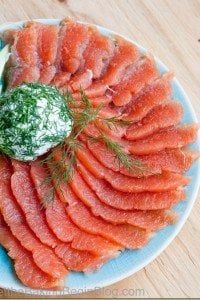 a blue plate topped with sliced up salmon and cucumber on top of a wooden table