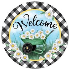 a green wheelbarrow with daisies and the words welcome in black and white checkered