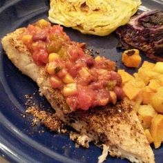 a blue plate topped with meat, potatoes and veggies next to an eggplant