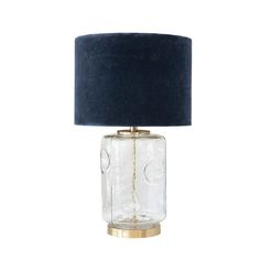 a clear glass table lamp with a blue shade on the top and gold trim around the base