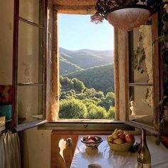 there is a table with fruit on it in front of a window that looks out onto the mountains