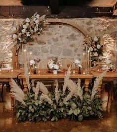 the table is set up with flowers and greenery for an elegant wedding reception in stone walls