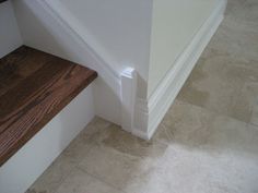 a wooden bench sitting on the side of a white wall next to a stair case