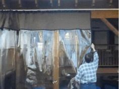 a man standing in front of a window covered in tarp and covering it with plastic