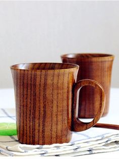 two wooden mugs sitting on top of a table next to a green pickle