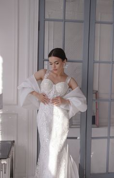 a woman in a white wedding dress leaning against a wall with her hands on her hips