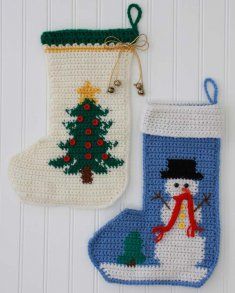 two crocheted christmas stocking ornaments hanging on a white wall next to a snowman ornament