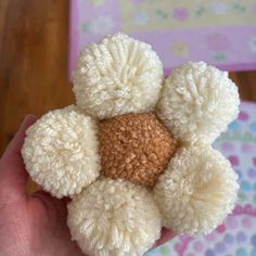 a hand holding a white and brown teddy bear