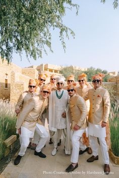 a group of men standing next to each other in front of a tree and building